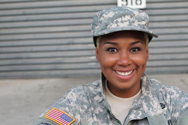 A smiling servicewoman in a camouflage uniform and cap.